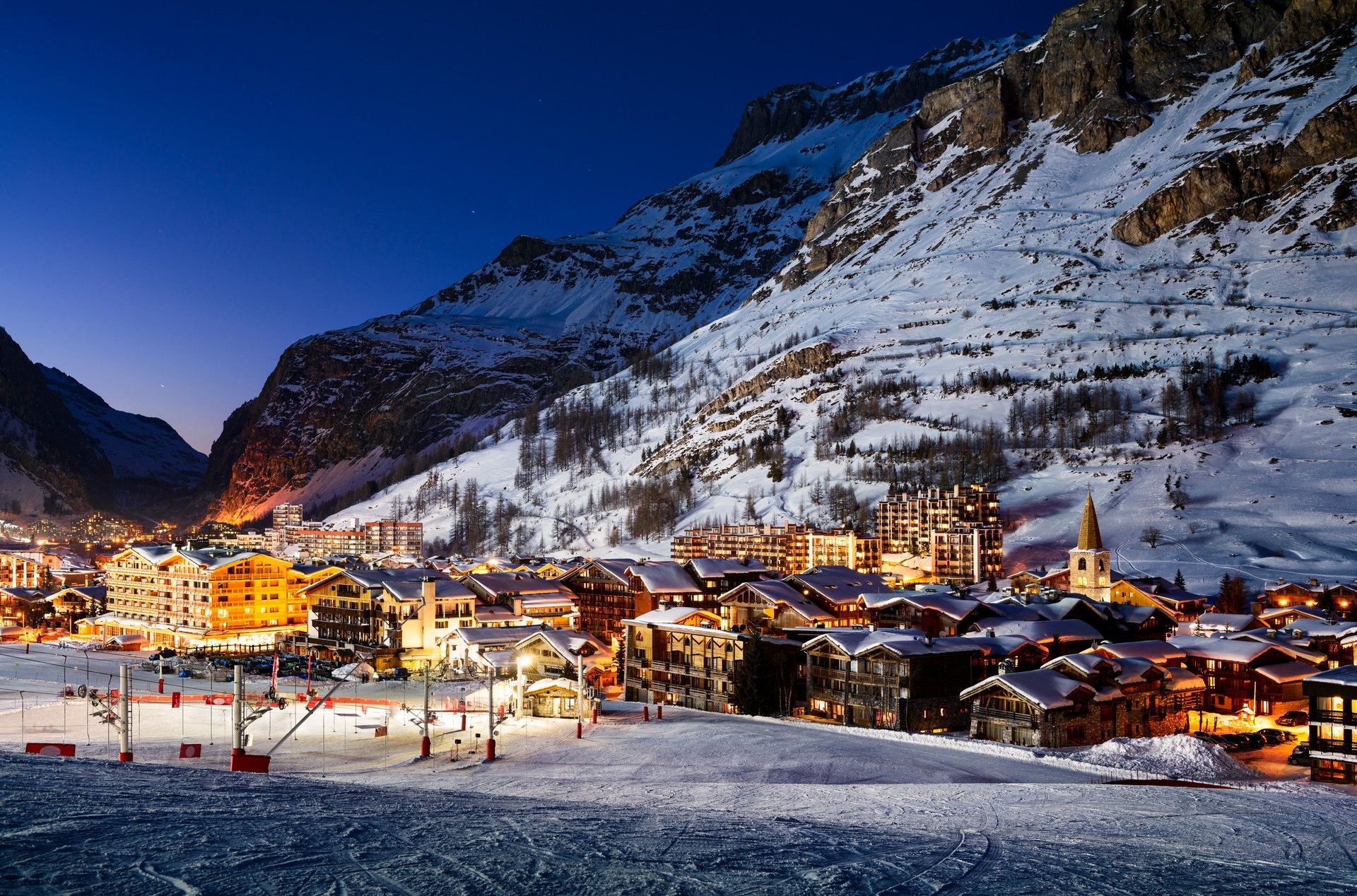 Village enneigé et chalets illuminés la nuit à Val d’Isère