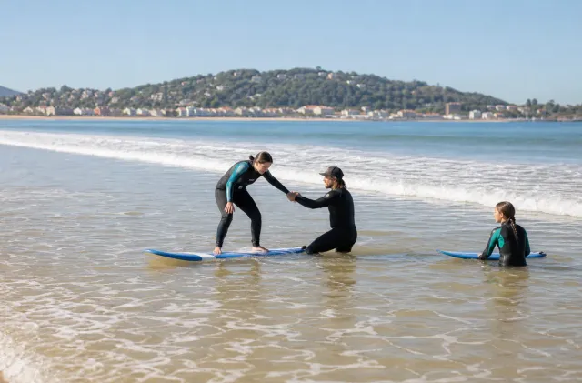 Moniteur aidant une débutante à se lever dans une mousse douce à la Grande Plage d'Hendaye.