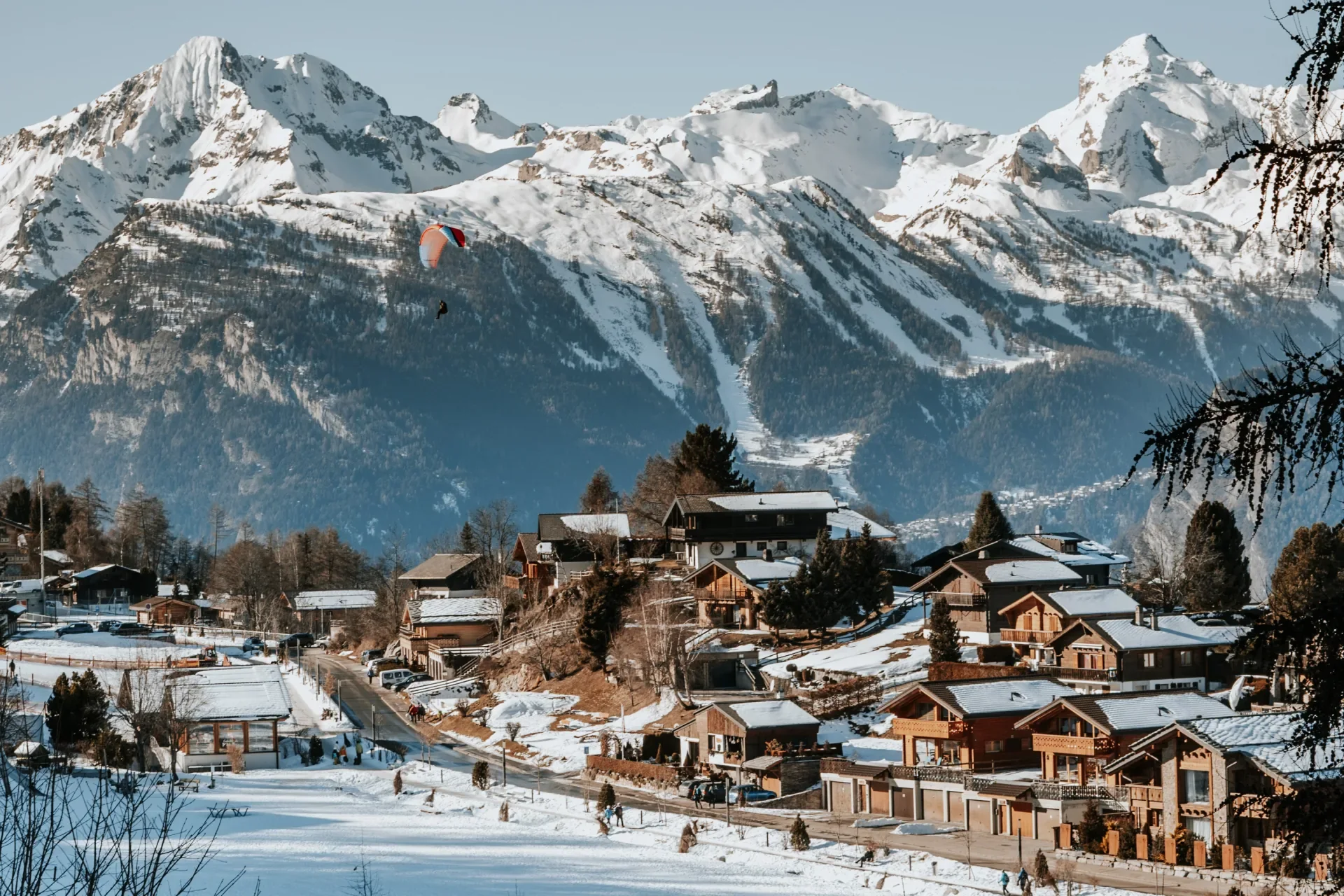 Parapente au-dessus du village hivernal de Nendaz et des sommets enneigés du Valais