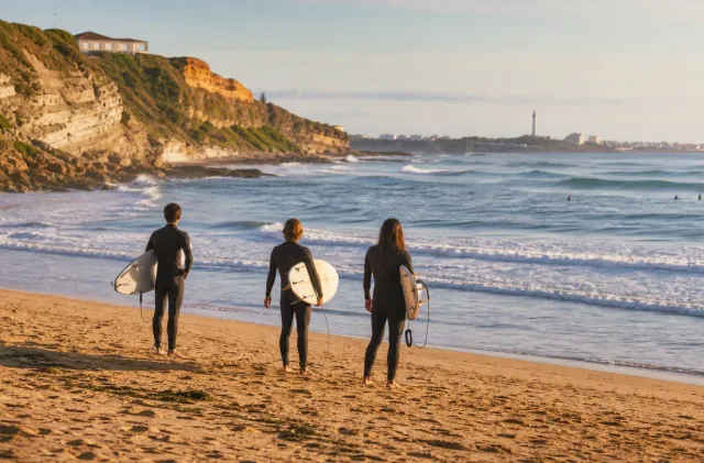 Surfeurs observant les vagues à la Chambre d'Amour à Anglet, avec falaises, plage et océan.
