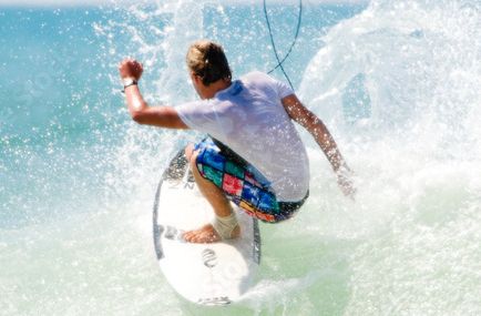 A surfer resting in the water with a board at sunset.