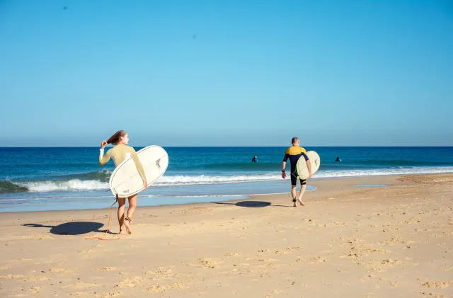 Surfeurs marchant vers l'océan pour un cours débutant sur la plage de La Sud à Hossegor.